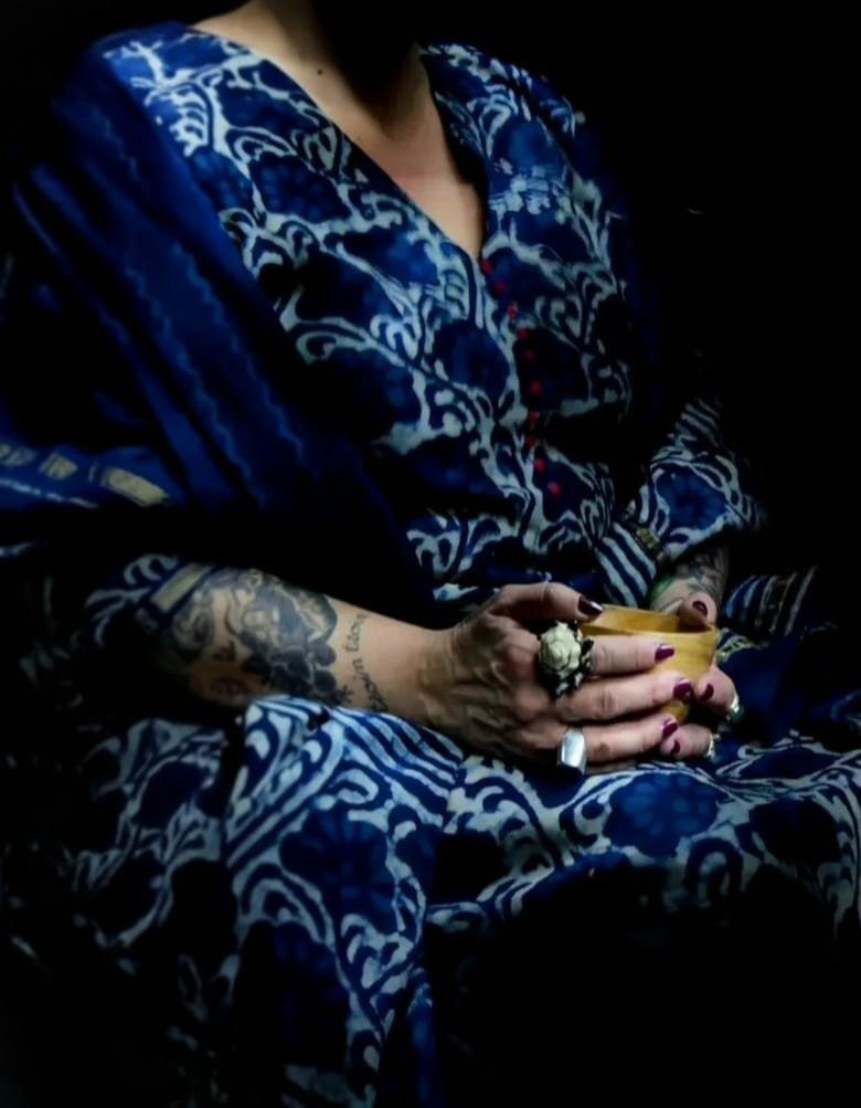 Les mains de Stéphanie tiennent une tasse, sur sa robe indigo imprimée